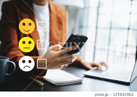 Customer service evaluation concept. woman Show face smile emoticon show on virtual screen from hand.looking at smart phone, tablet and laptop 125682062