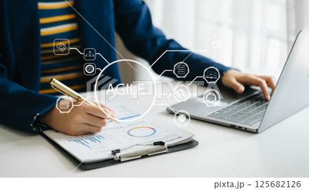 Agile development methodology concept. Business hand using laptop computer and tablet with virtual screen Agile icon on modern office 125682126