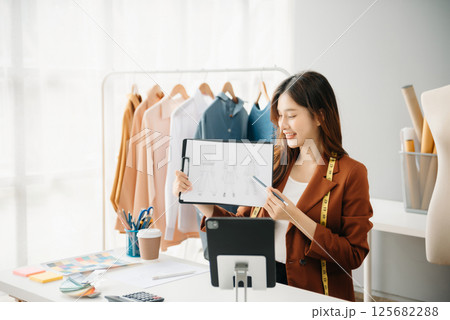 Diverse female fashion designers at work with tailor centimeters on necks and holds tablet and smartphone. independent creative design 125682288