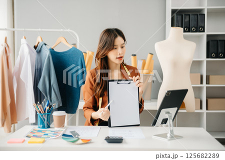 Diverse female fashion designers at work with tailor centimeters on necks and holds tablet and smartphone. independent creative design 125682289