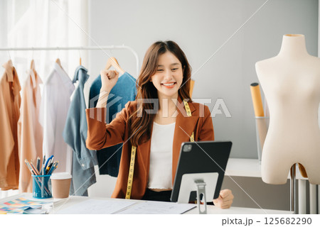 Diverse female fashion designers at work with tailor centimeters on necks and holds tablet and smartphone. independent creative design 125682290