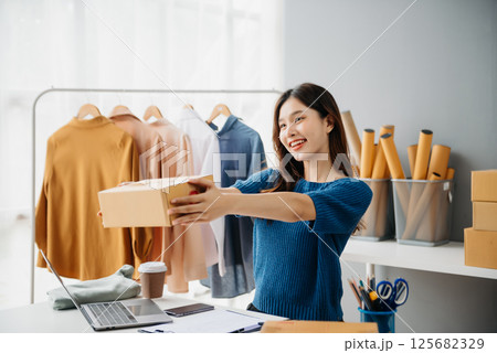 Asian lady blogger showing clothes in front of the camera to recording vlog video live streaming at her shop. Online Shopping Asian lady blogger showing clothes in front of the camera to recording vlog video live streaming at her shop. Online Shopping 125682329