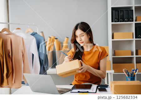 Young woman running online store Startup small business SME, using smartphone or tablet taking receive and checking online purchase shopping Young woman running online store Startup small business SME, using smartphone or tablet taking receive and checking online purchase shopping 125682334