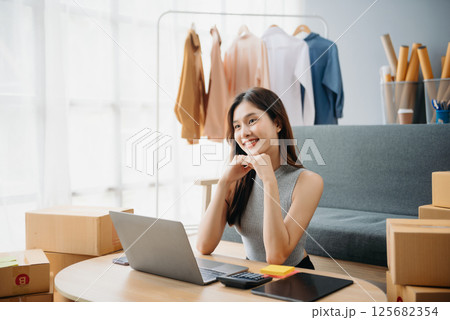 Asian lady blogger showing clothes in front of the camera to recording vlog video live streaming at her shop. Online Shopping 125682354