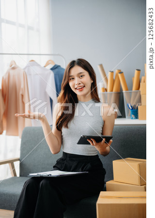 Asian lady blogger showing clothes in front of the camera to recording vlog video live streaming at her shop. Online Shopping Asian lady blogger showing clothes in front of the camera to recording vlog video live streaming at her shop. Online Shopping 125682433