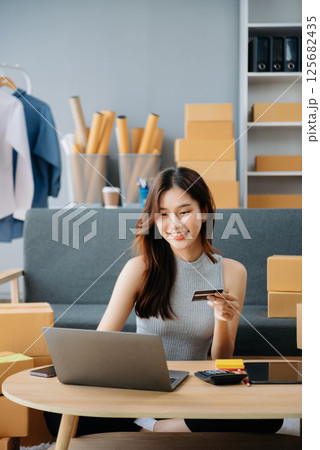 Asian lady blogger showing clothes in front of the camera to recording vlog video live streaming at her shop. Online Shopping 125682435