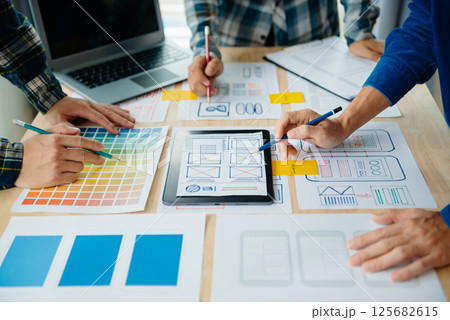 UX developer and ui designer brainstorming about mobile app interface wireframe design with customer breif and color code at modern office. UX developer and ui designer brainstorming about mobile app interface wireframe design with customer breif and color code at modern office. 125682615