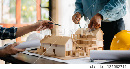 Two architects discussing new project. young men and women working together to form a new building. Two architects discussing new project. young men and women working together to form a new building. 125682711