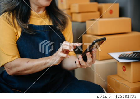 Mature business owner woman prepare parcel box and standing check online orders for deliver to customer on tablet, laptop Shopping Online Mature business owner woman prepare parcel box and standing check online orders for deliver to customer on tablet, laptop Shopping Online 125682733
