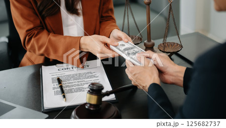 justice and law concept.passing bribe money in the envelop at lawyer office. businessman hand taking bribe money from female justice and law concept.passing bribe money in the envelop at lawyer office. businessman hand taking bribe money from female 125682737