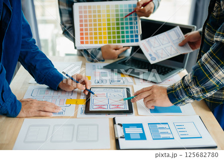 UX developer and ui designer brainstorming about mobile app interface wireframe design with customer breif and color code at modern office. 125682780