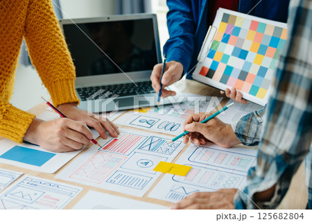View of UI developer team brainstorming on their project with laptop, smartphone and digital tablet. Creative digital development agency. View of UI developer team brainstorming on their project with laptop, smartphone and digital tablet. Creative digital development agency. 125682804