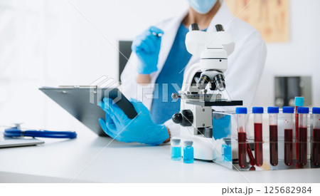 Young scientists conducting research investigations in a medical laboratory, a researcher in the foreground is using a microscope in laboratory for medicine. 125682984