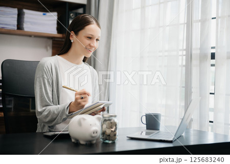 Caucasian Women are putting coins in a piggy bank for a business that grows for profit and saving money for the future. Caucasian Women are putting coins in a piggy bank for a business that grows for profit and saving money for the future. 125683240