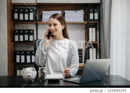 Caucasian Women are putting coins in a piggy bank for a business that grows for profit and saving money for the future. Caucasian Women are putting coins in a piggy bank for a business that grows for profit and saving money for the future. 125683243