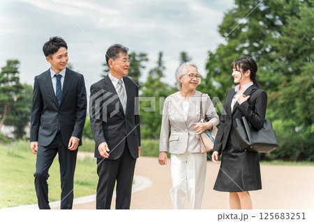 公園を歩くスーツ姿のシニア世代とZ世代のビジネスマンとビジネスウーマン 125683251