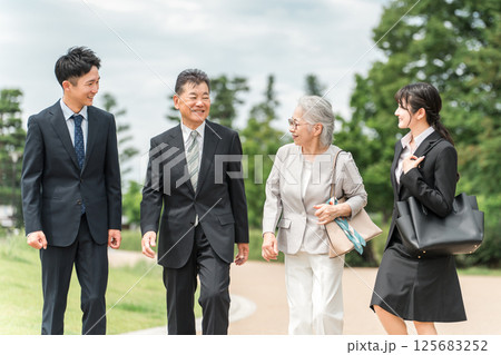 公園を歩くスーツ姿のシニア世代とZ世代のビジネスマンとビジネスウーマン 125683252