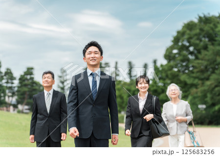スーツ姿の若者とシニアの男女ビジネスマン（M&A・後継者・事業継承・跡取り・売却・買収・世代交代） 125683256