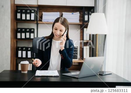 Beautiful woman using laptop and tablet while sitting at her working place. Concentrated at work. 125683311