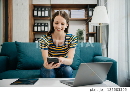 Caucasian businesswoman working in the office with working notepad, tablet and laptop documents on sofa in home office 125683396