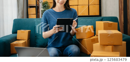 Caucasian young woman SME working using smartphone or tablet taking receive and checking online purchase shopping order to freelance online concept. Caucasian young woman SME working using smartphone or tablet taking receive and checking online purchase shopping order to freelance online concept. 125683479