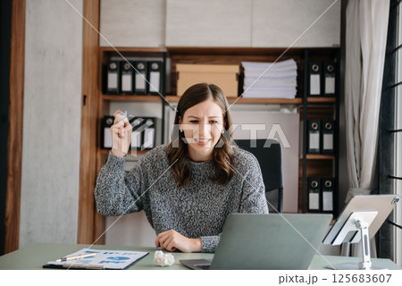 Bsiness woman is stressed, bored, and overthinking from working on a tablet at the modern office. 125683607