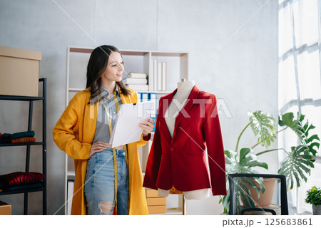 Diverse female fashion designers at work with tailor centimeters on necks and holds tablet and smartphone. 125683861