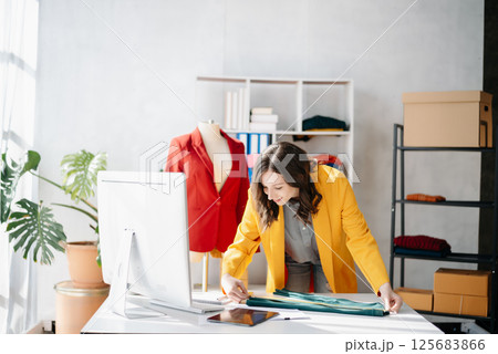 Diverse female fashion designers at work with tailor centimeters on necks and holds tablet and smartphone. 125683866