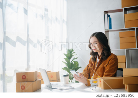 Young business owner woman prepare parcel box and standing check online orders for deliver to customer on tablet, laptop Shopping Online concept. Young business owner woman prepare parcel box and standing check online orders for deliver to customer on tablet, laptop Shopping Online concept. 125683950