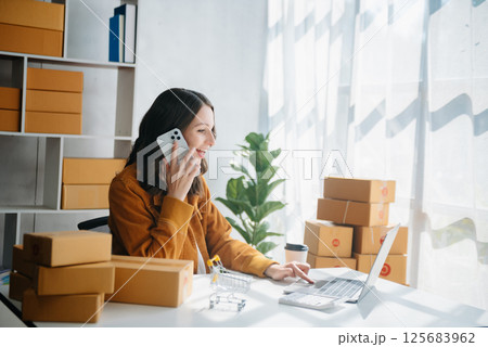 Young business owner woman prepare parcel box and standing check online orders for deliver to customer on tablet, laptop Shopping Online concept. 125683962