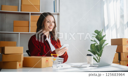 Young business owner woman prepare parcel box and standing check online orders for deliver to customer on tablet, laptop Shopping Online concept. 125683964