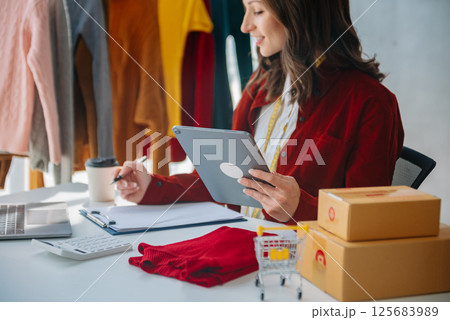 Fashion designer woman talking smart phone and using laptop with digital tablet computer in modern studio Fashion designer woman talking smart phone and using laptop with digital tablet computer in modern studio 125683989