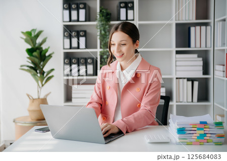 Beautiful woman using laptop and tablet while sitting at her working place. Concentrated at work. 125684083