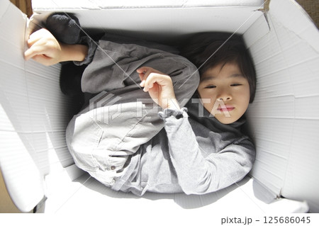 段ボールの箱の中でまったりとしている少年 125686045