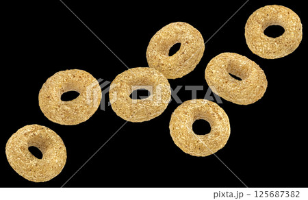 Falling cereal rings isolated on black background, package design element 125687382
