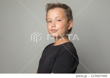 Handsome serious school age boy in black t-shirt looking at camera on white background Handsome serious school age boy in black t-shirt looking at camera on white background 125687400