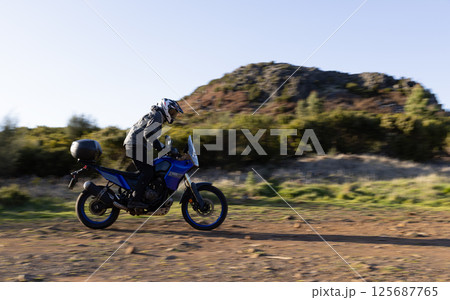 Driver riding motorcycle on empty asphalt road, spring mountains Driver riding motorcycle on empty asphalt road, spring mountains 125687765