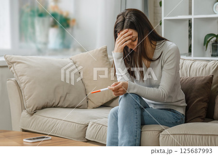 Sad woman looking at negative pregnancy test Sad woman looking at negative pregnancy test 125687993