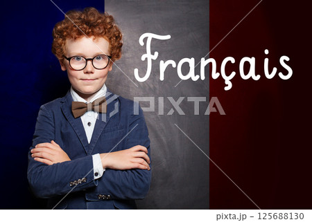Confident child boy with crossed arms on French flag with the inscription Francais in French. Confident child boy with crossed arms on French flag with the inscription Francais in French. 125688130