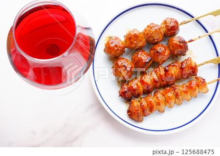 炭火でじっくり焼き上げたおいしそうな焼き鳥(つくね串と、ぼんじり)と、赤ワインのグラス 炭火でじっくり焼き上げたおいしそうな焼き鳥(つくね串と、ぼんじり)と、赤ワインのグラス 125688475