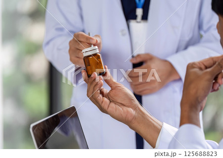 Doctor handing over prescription medication to a colleague for consultation 125688823