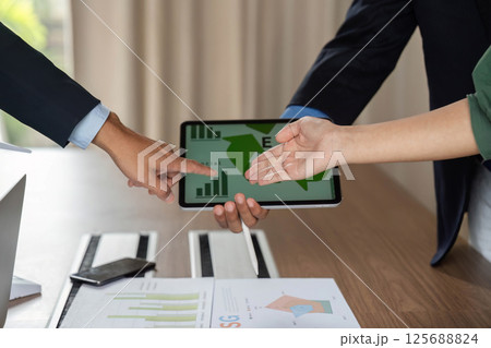 ESG discussions with tablet showcasing data and diverse teamwork ESG discussions with tablet showcasing data and diverse teamwork 125688824