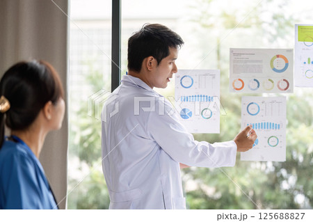 Doctor presenting analysis data to a colleague during a meeting 125688827