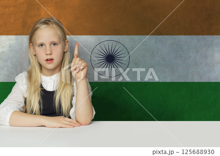Adorable young child girl pointing up on flag of India background. Adorable young child girl pointing up on flag of India background. 125688930