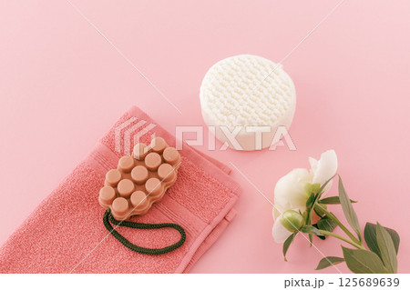 Towel with body care products and a peony flower on the pink background. Towel with body care products and a peony flower on the pink background. 125689639