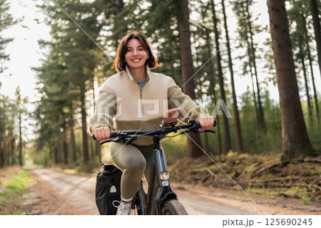 Solo cyclist coasts through green forest trails, blending summer vacation spirit with healthy lifestyle and nature-based sport 125690245