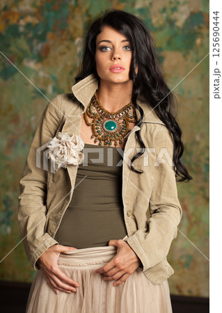 Lovely young fashion woman standing against green stucco wall background 125690444