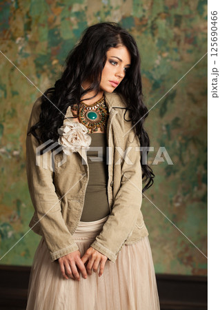 Pretty young fashion woman standing against green stucco wall background 125690466