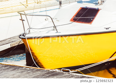 Yellow sailboat moored at marina dock with sunlit reflections, background Yellow sailboat moored at marina dock with sunlit reflections, background 125692323