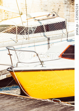 Sailboats moored in sunny marina with vibrant yellow hulls, creating a nautical background 125692324